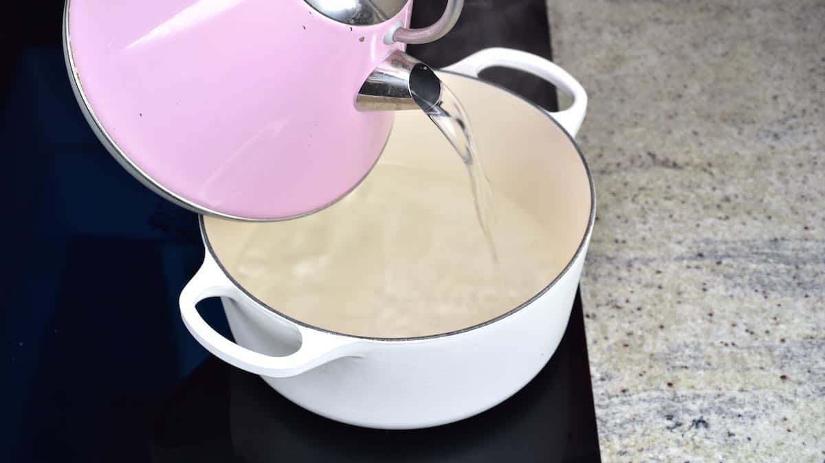 Pouring hot water from kettle to pot
