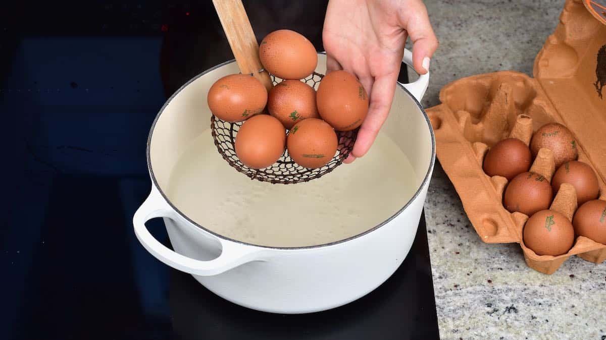 Adding eggs to hot water in pot
