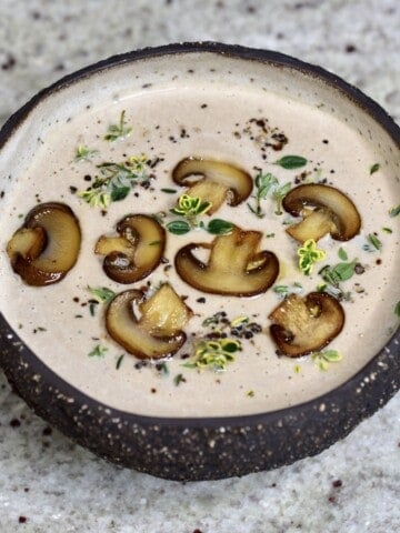 A bowl with mushroom soup topped with slices of mushrooms