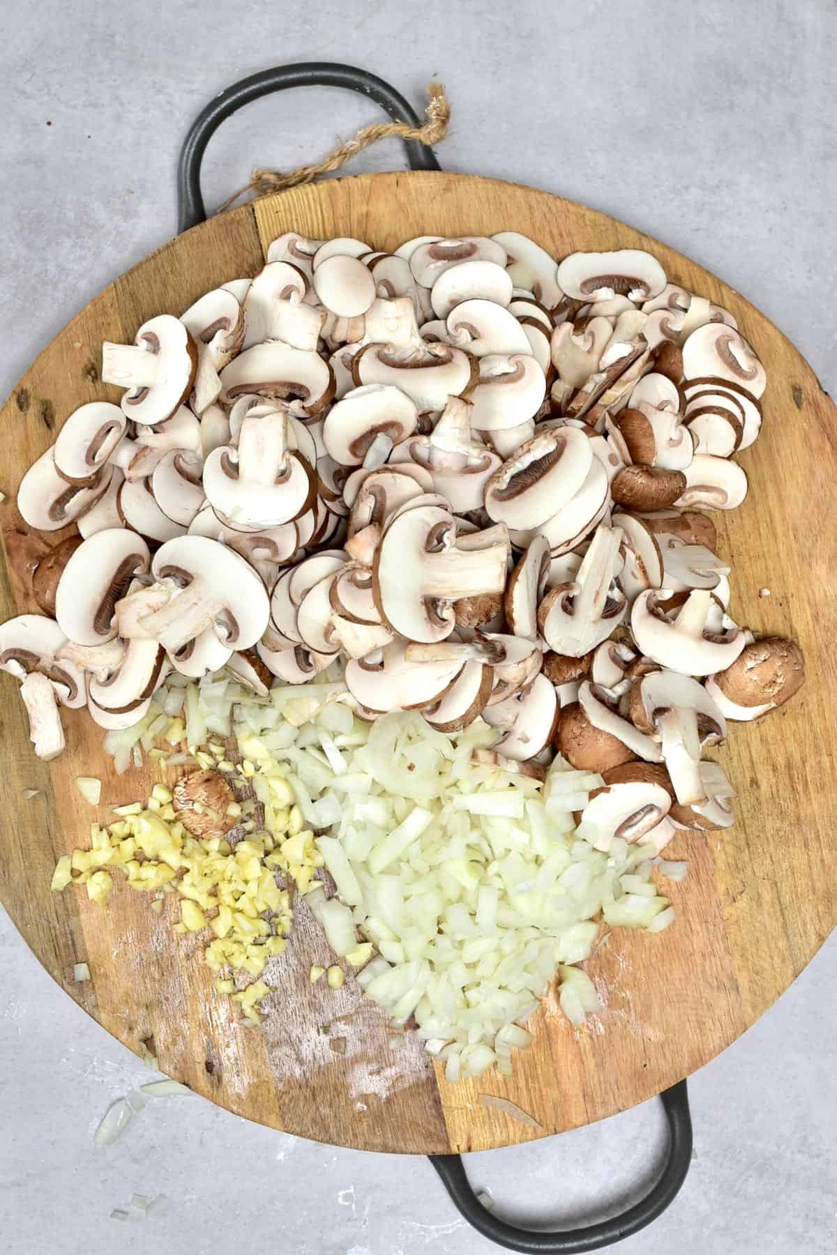 Chopped onion, garlic and mushrooms on a wooden board