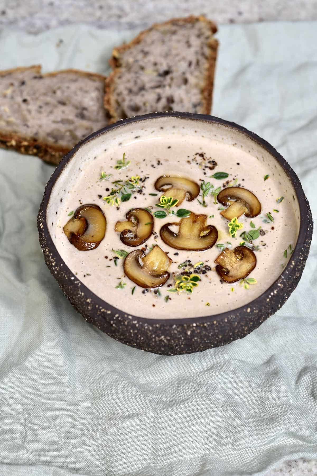 A bowl with mushroom soup topped with slices of mushrooms