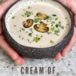 A bowl of mushroom soup topped with mushrooms and thyme