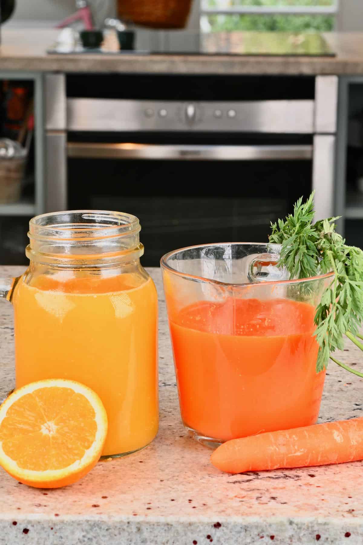 Mason jar with orange juice and measuring cup with carrot juice
