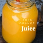 A mason jar with orange juice and a glass straw