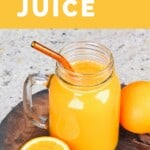 A mason jar with orange juice and a glass straw and an orange next to it