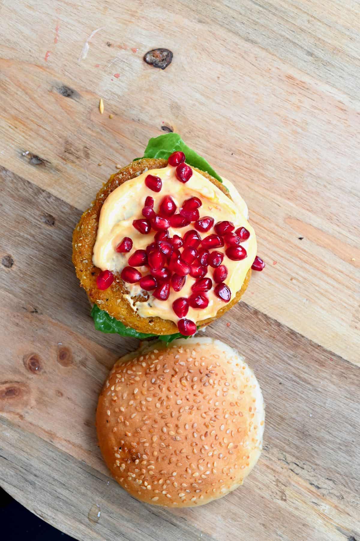 Assembling a burger with added spicy mayo and pomegranate seeds