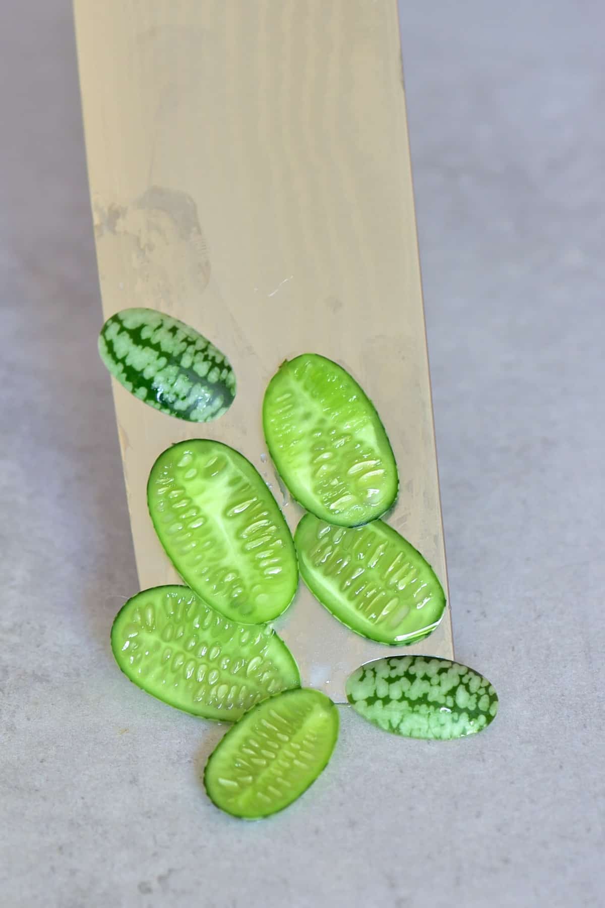 Sliced cucamelon berries placed on a knife