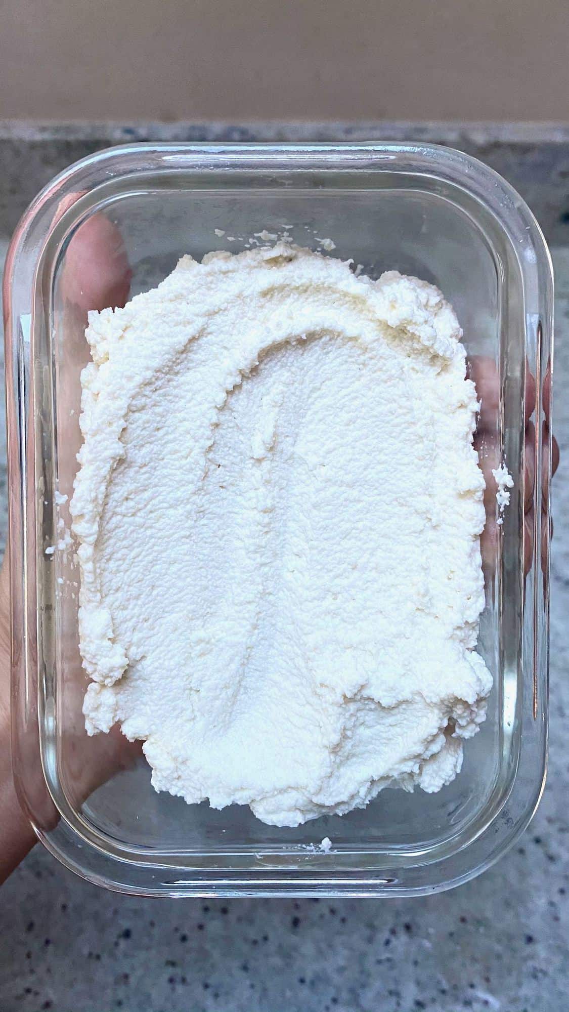 A glass container with almond vegan ricotta
