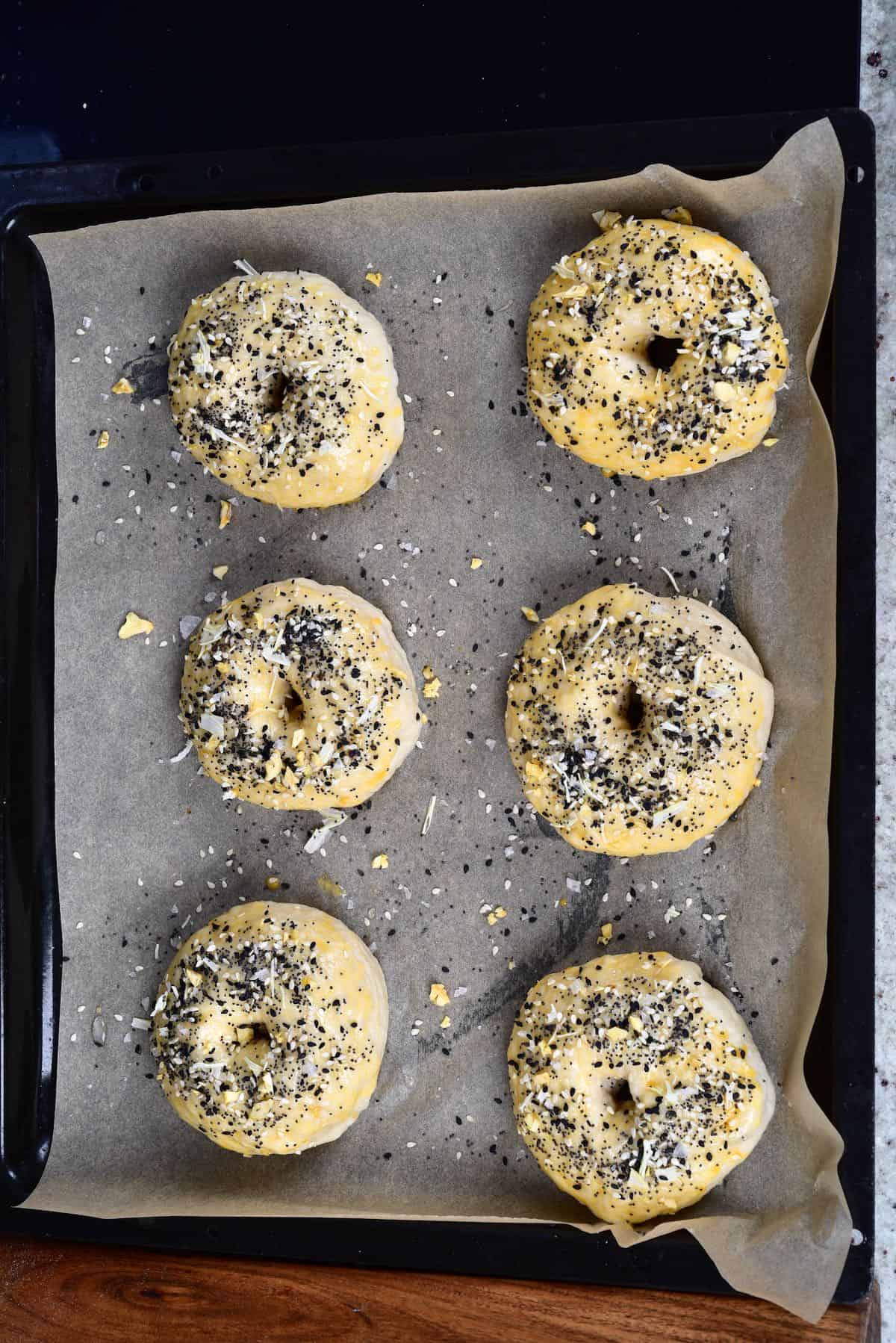 Six bagels in a baking tray ready to bake