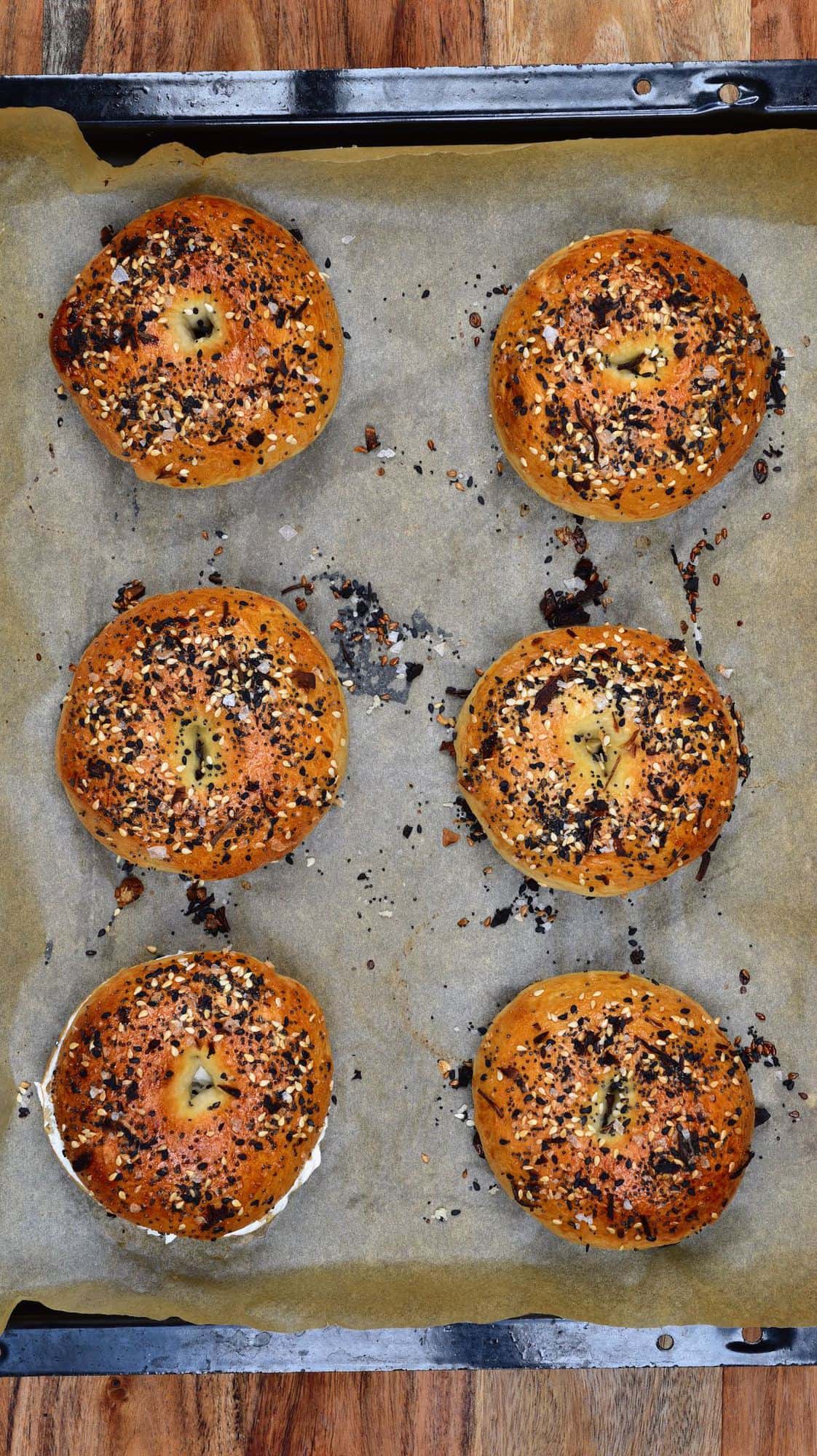 Six freshly baked bagels in a baking tray