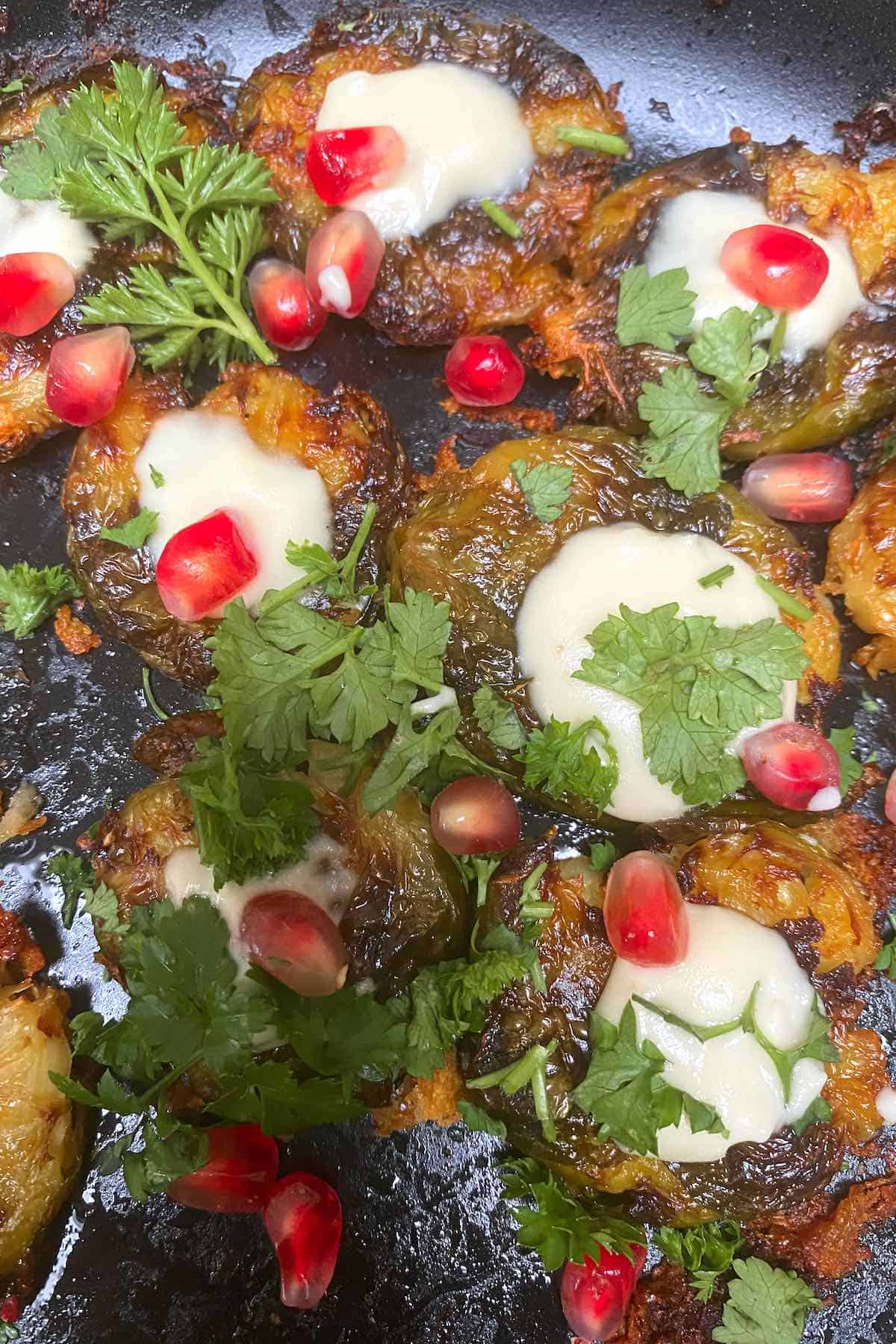 Roasted Brussels sprouts topped with sauce and pomegranate