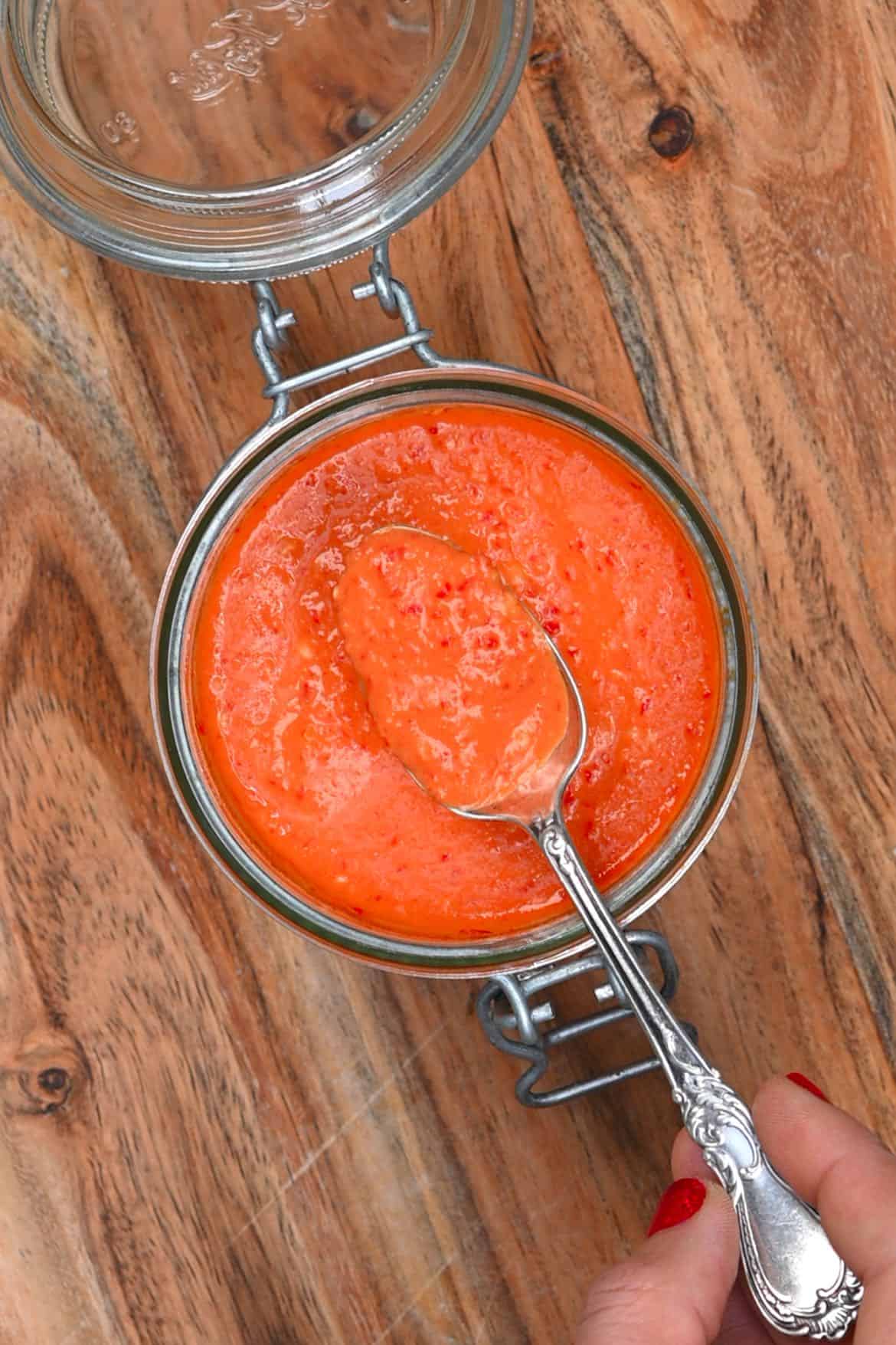 Homemade chili sauce being spooned out of a jar