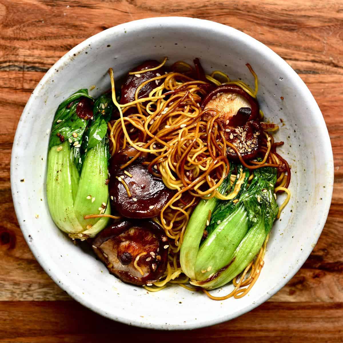 Dan dan noodles with bok choy and mushrooms in a bowl