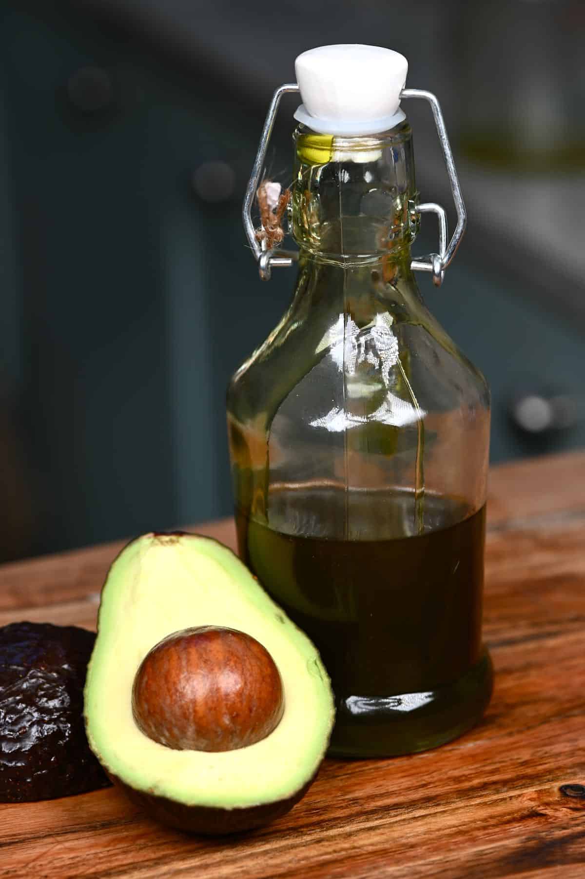 Half an avocado and a small bottle with avocado oil
