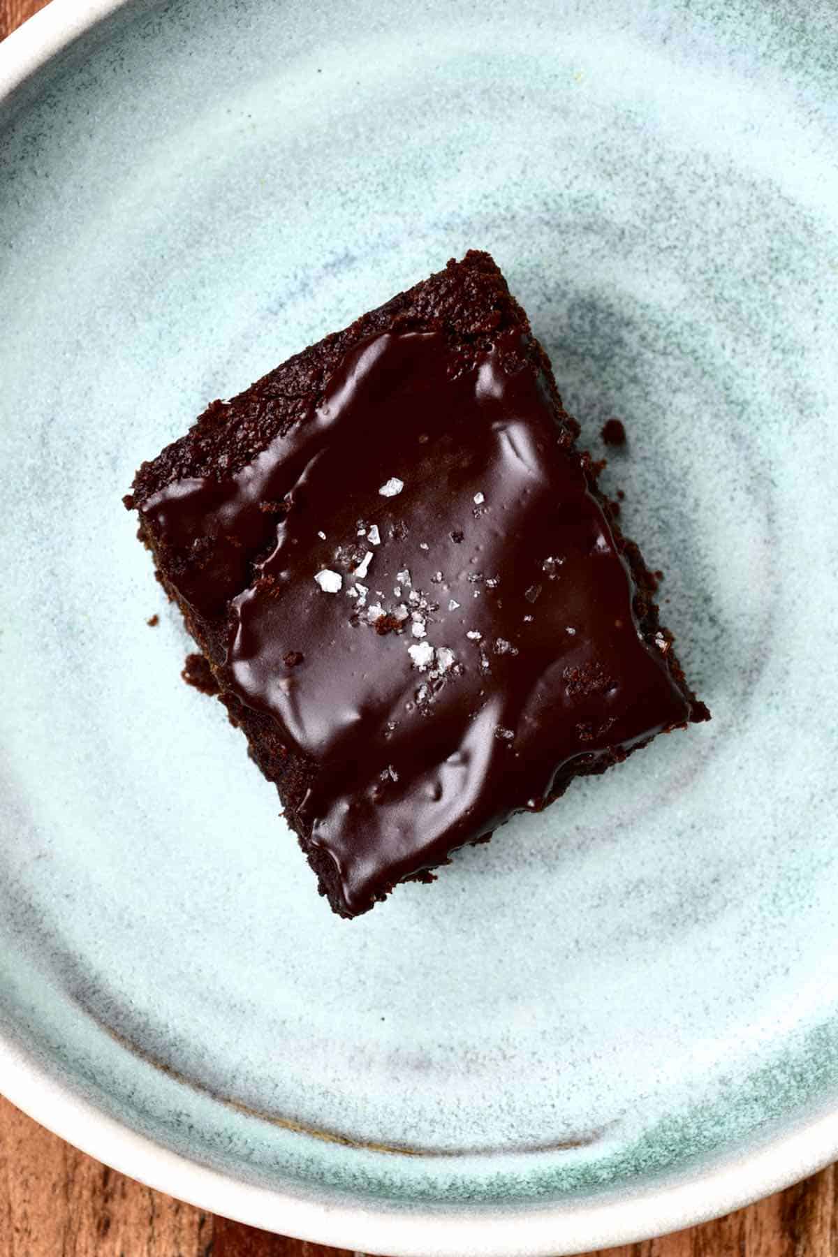 A piece of brownie in a plate with some salt