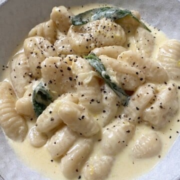 Gnocchi in a bowl topped with black pepper and sage
