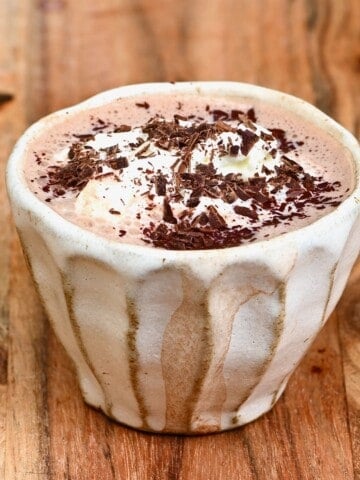 Hot chocolate in a small cup with chocolate shavings on top