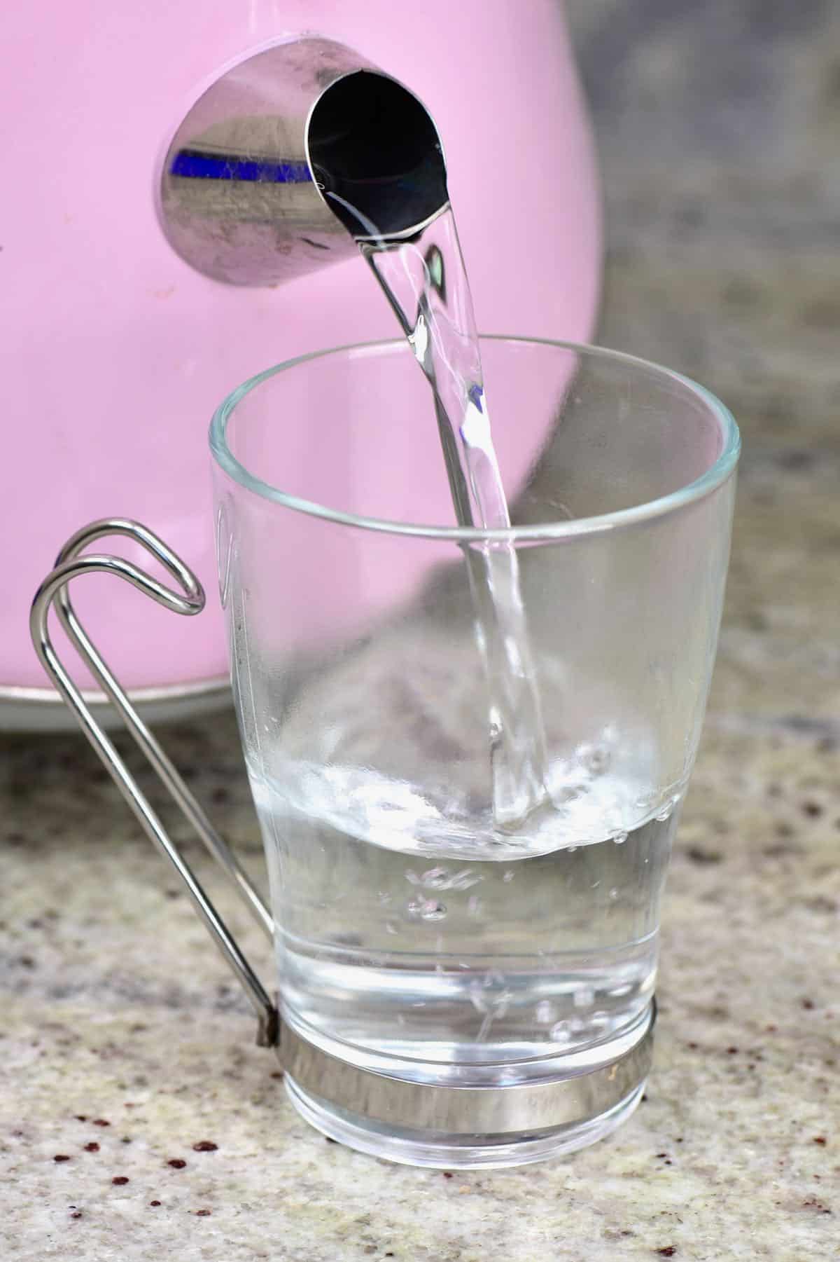 Pouring hot water from kettle to glass