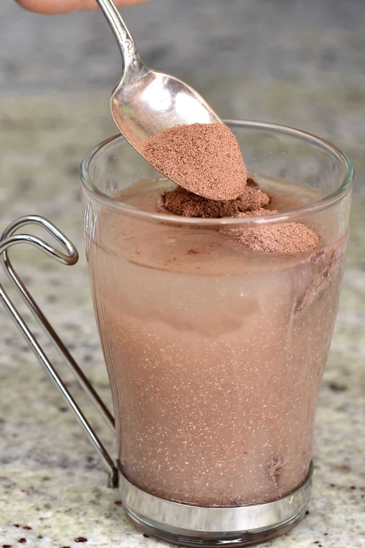 Adding hot chocolate mix to a glass of water