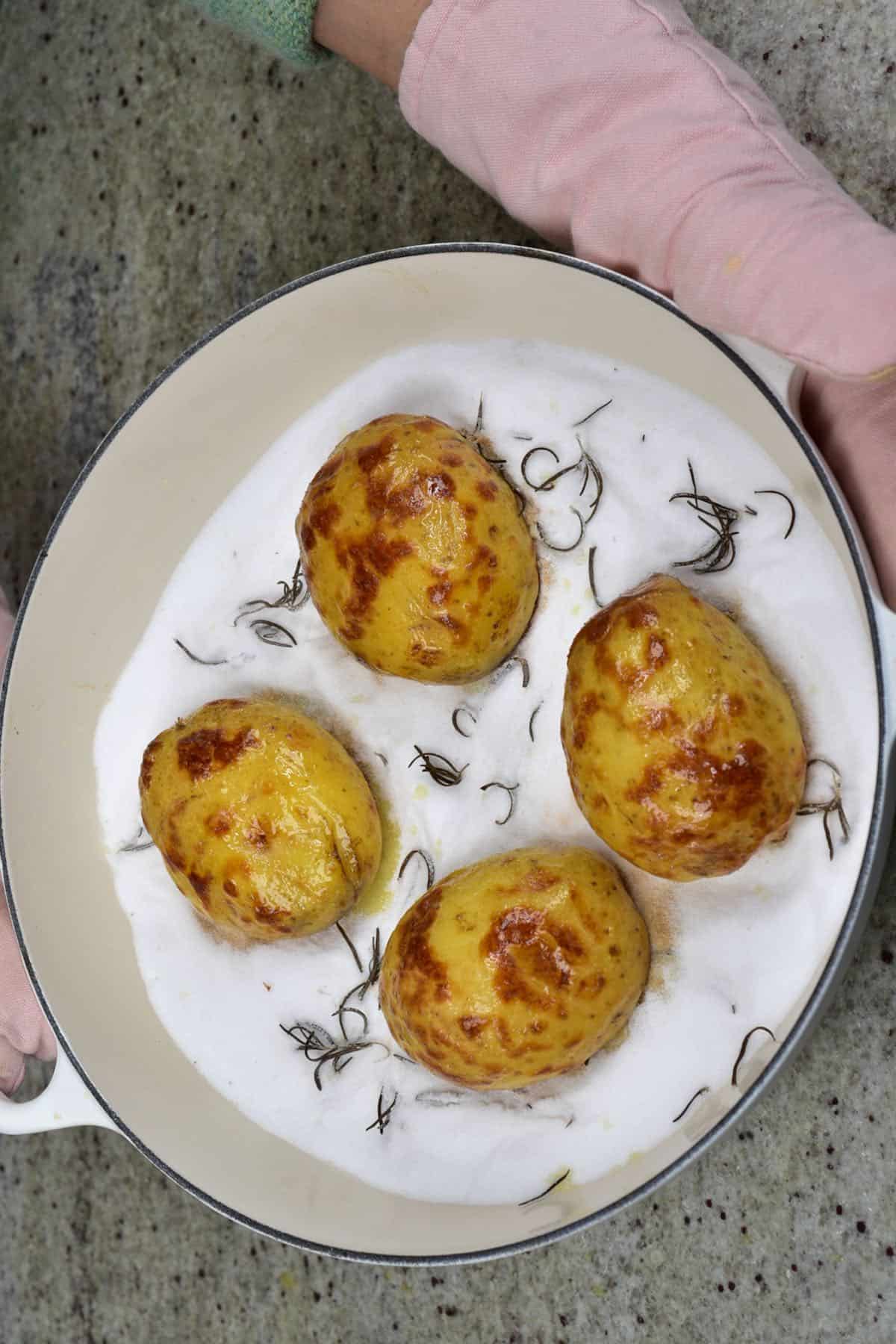 Four salt-baked potatoes in a baking dish