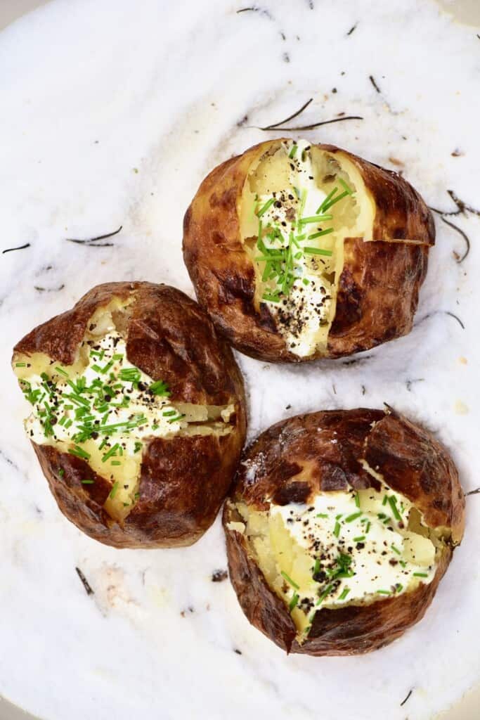 Three salt baked potatoes topped with cream and herbs