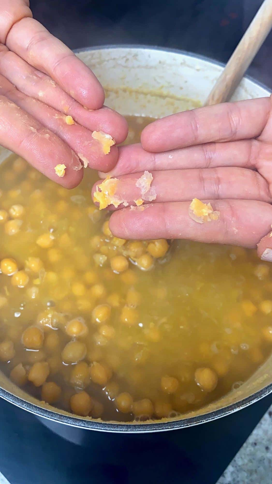 Showing softness of boiled chickpeas by smashing them with fingers