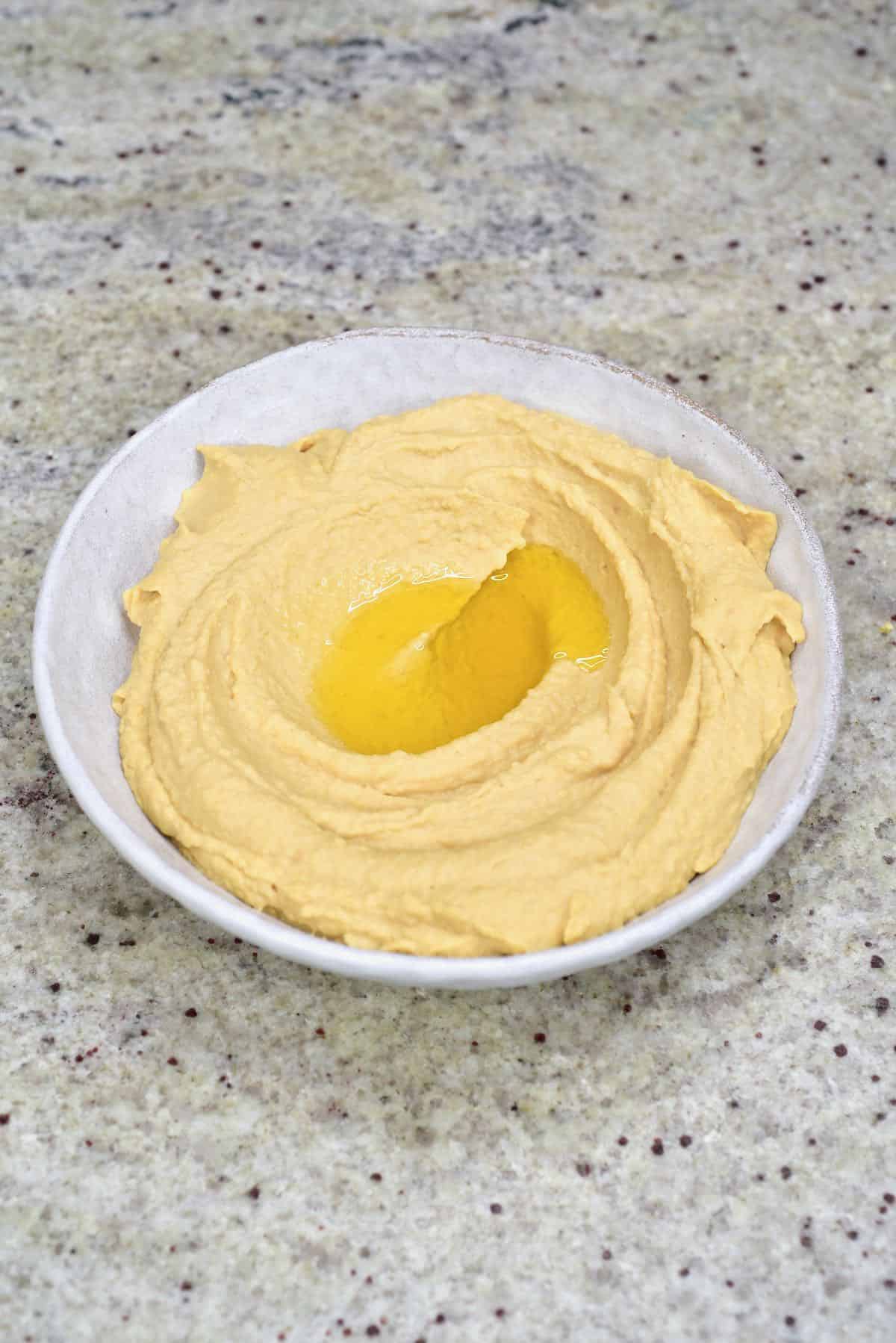 A bowl with hummus topped with some oil
