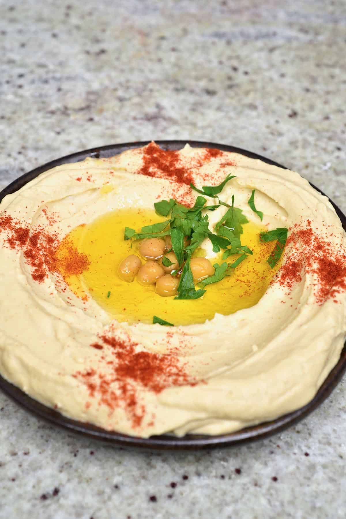 A bowl with hummus topped with some oil, chickpeas, paprika and coriander