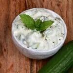 A small bowl with Yogurt Cucumber Salad topped with fresh mint leaves - 15