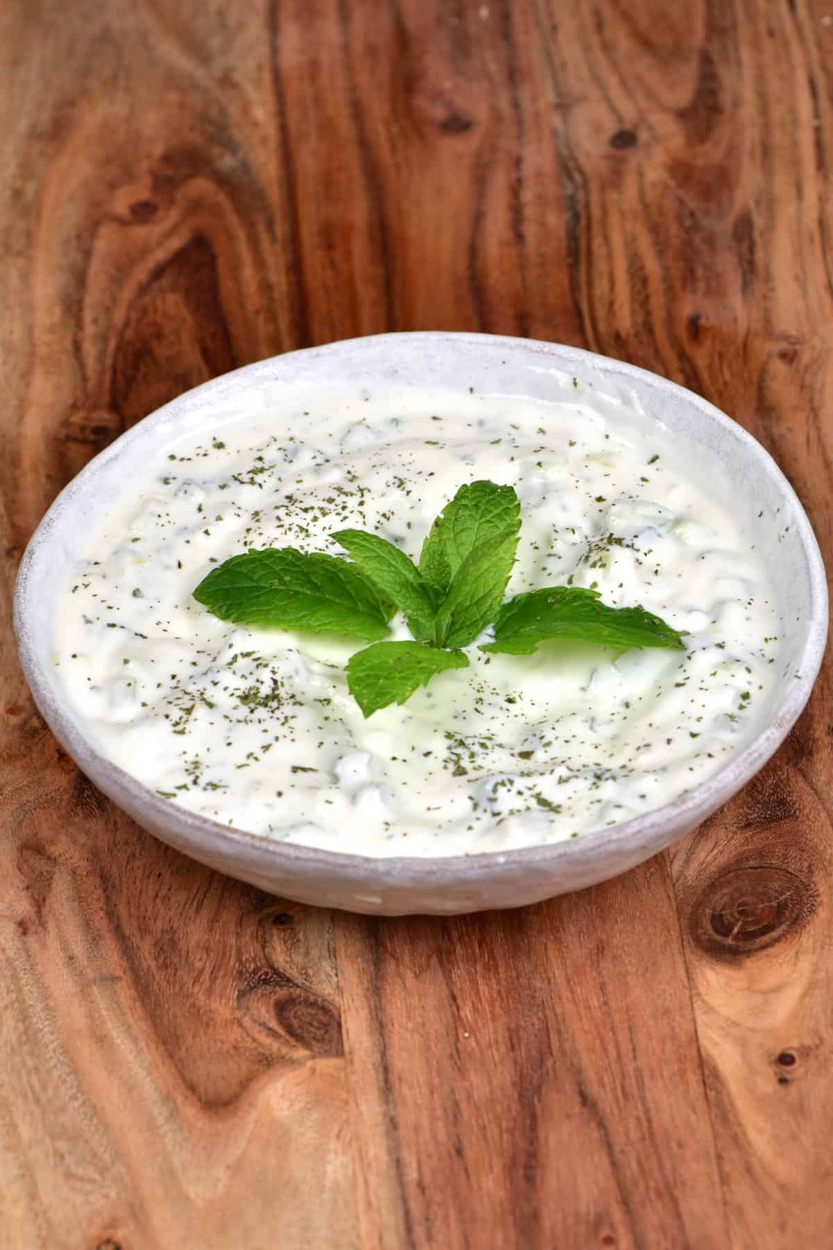 Yogurt Cucumber Salad served in a bowl and topped with fresh mint leaves