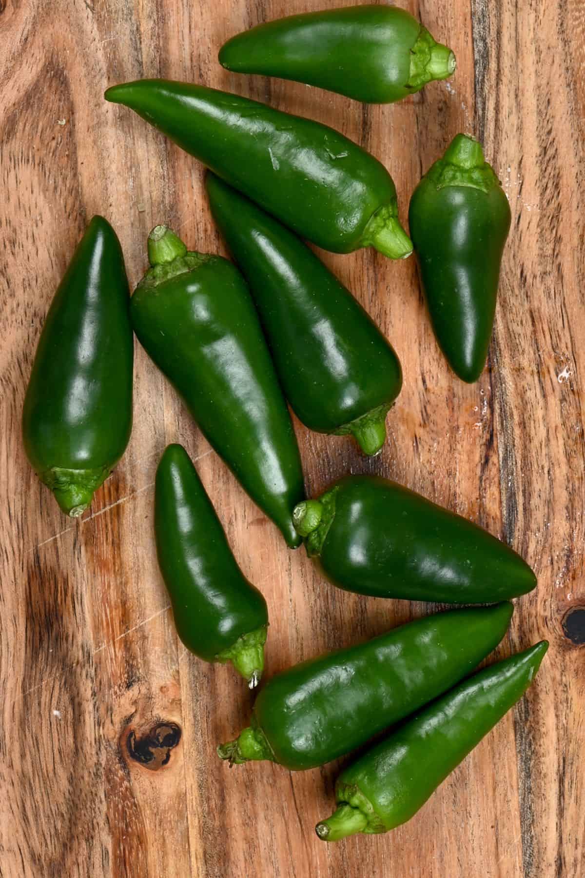 A few jalapeños on a wooded board