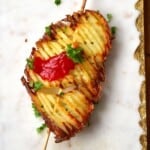 Accordion potato chip on a skewer topped with some parsley and ketchup