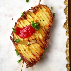 Accordion potato chip on a skewer topped with some parsley and ketchup