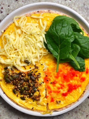 Tortilla topped with omelette cheese spinach and seeds