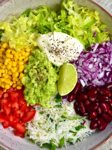 Rainbow veggies like lettuce, corn, beans, tomatoes and avocado in a bowl