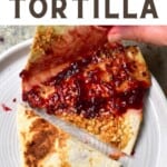 Tortilla topped with peanut butter, raspberry jelly and crushed nuts