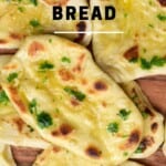 Several garlic naan on a flat wooden surface