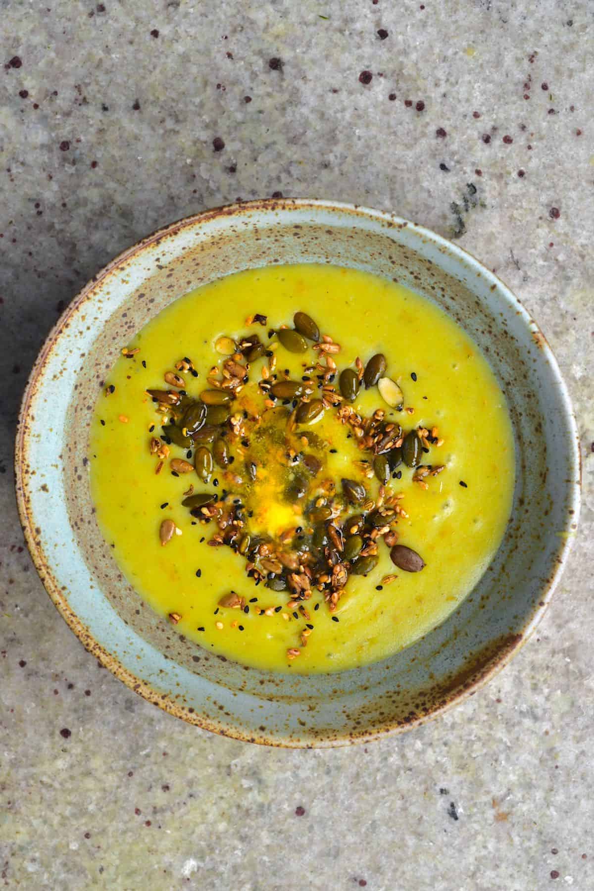 A bowl with potato leek cram soup topped with seeds