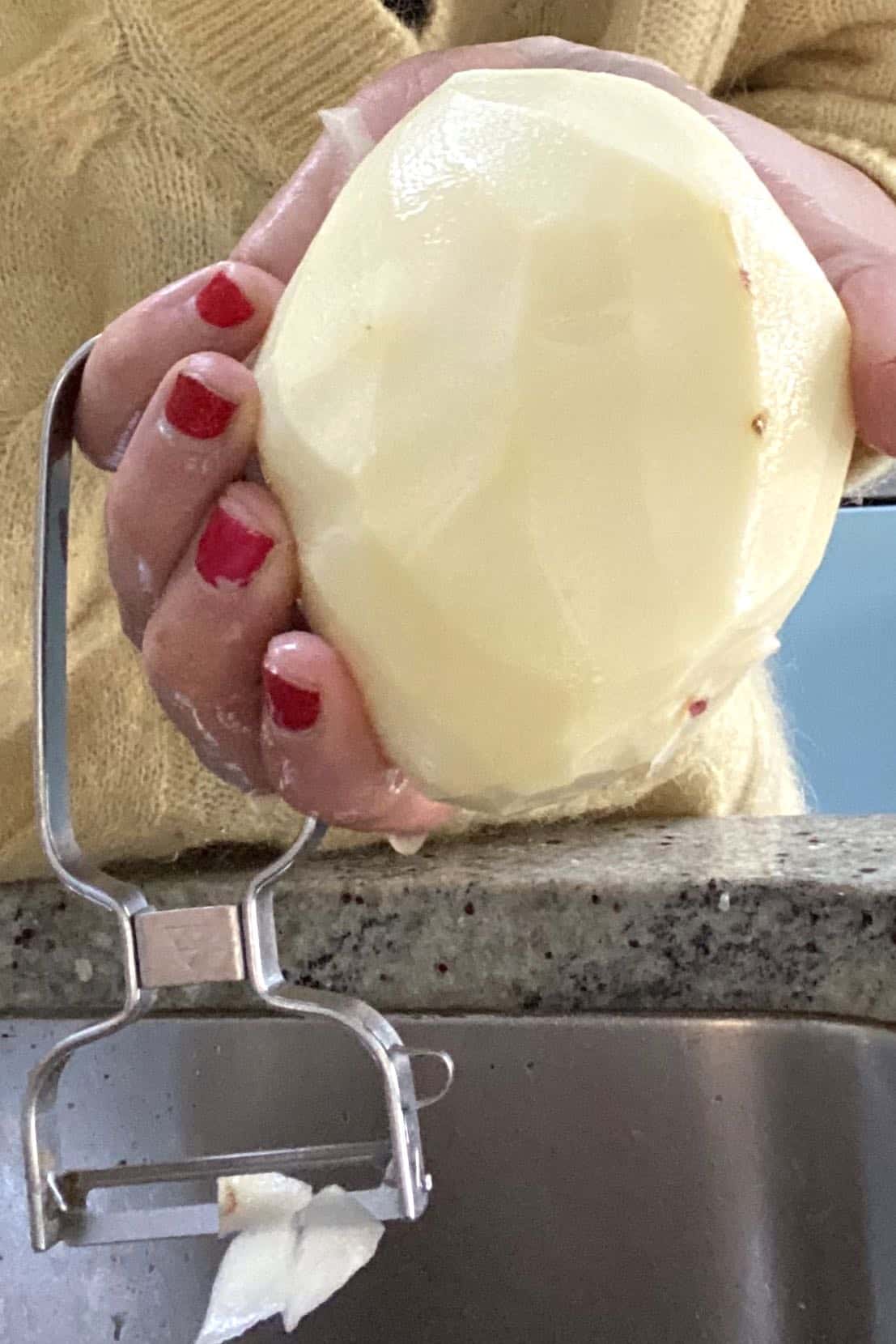 A hand holding a peeled potato
