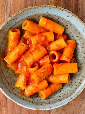 A bowl with penne pasta and tomato sauce topped with parmesan
