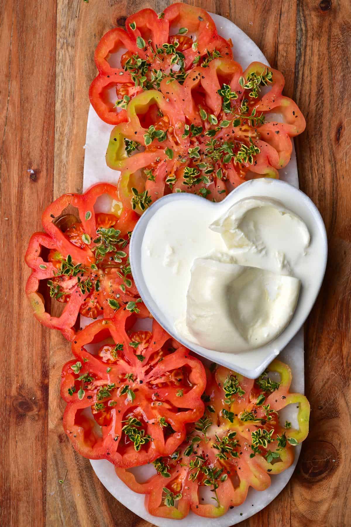 Tomatoes topped with lime thyme and some burrata cheese