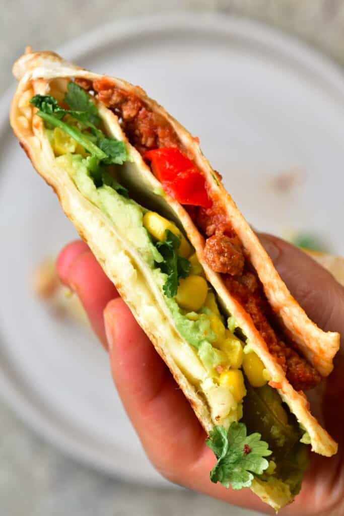 Tortilla wrap with vegan chili con carne, corn and avocado