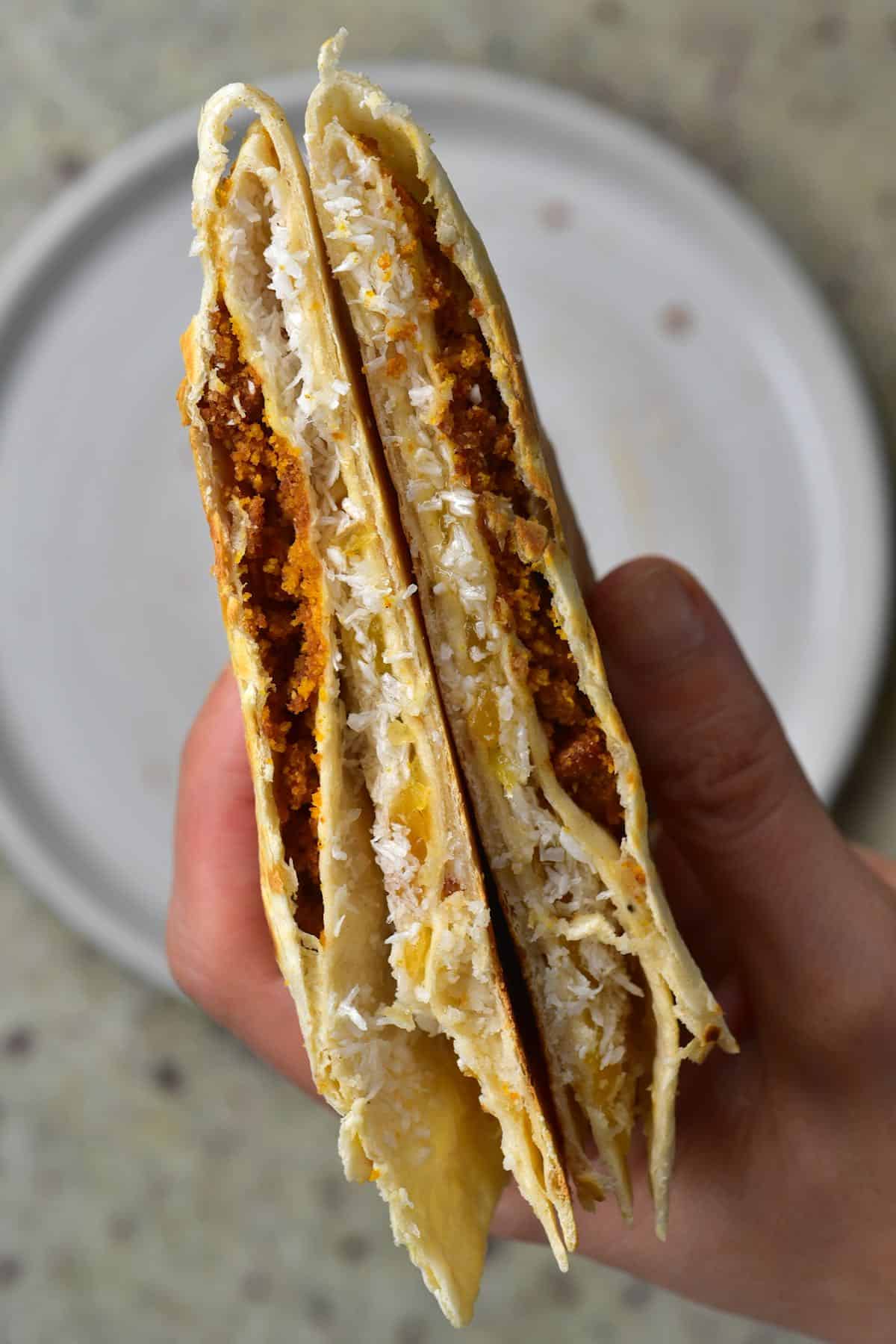 A hand holding wrapped tortilla with coconut and ginger