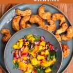 A plate with crispy baked shrimp and a bowl with mango salsa