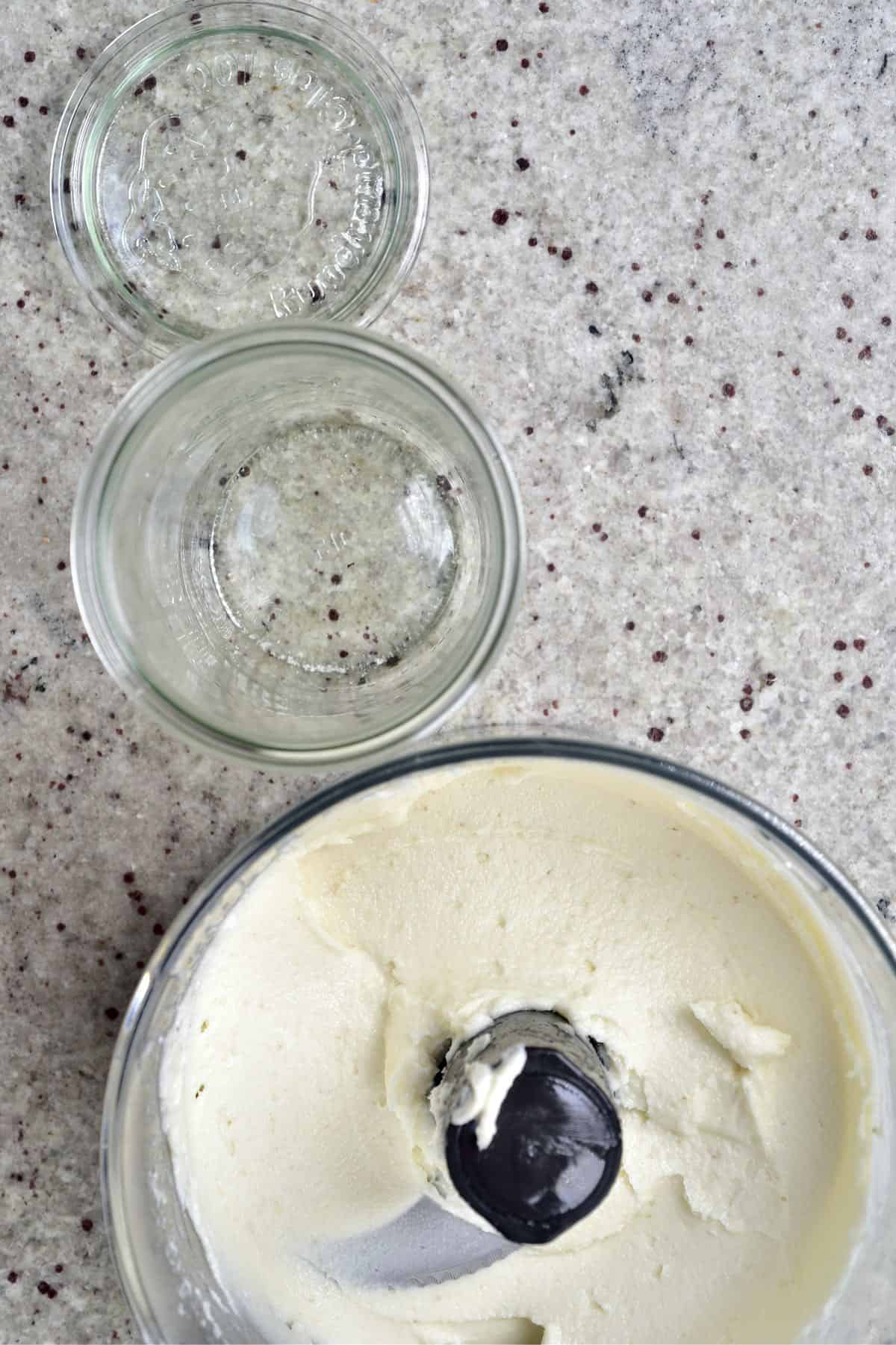 Food processor with garlic sauce and an empty jar