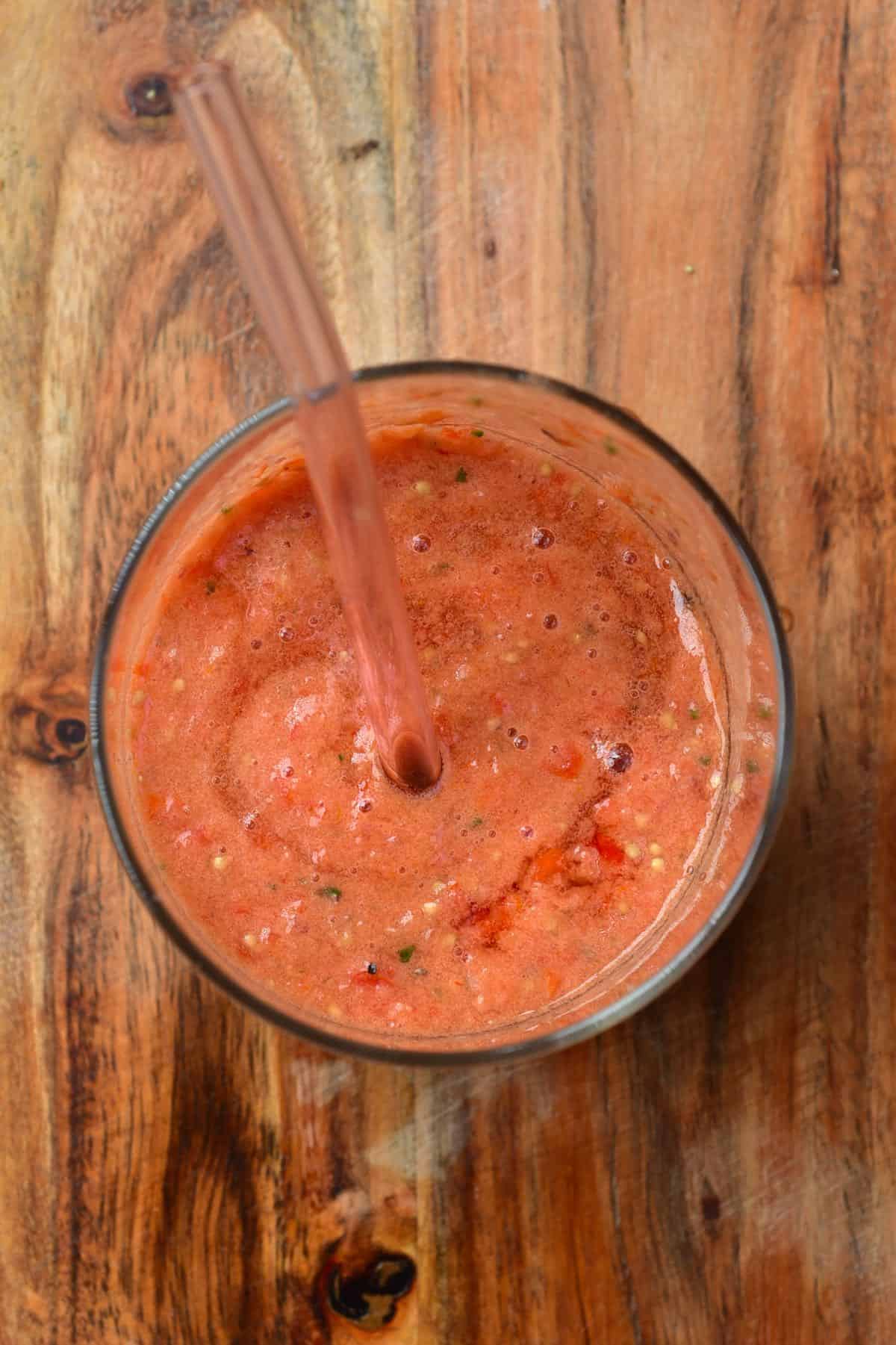 Top view of a glass full with gazpacho with a glass straw