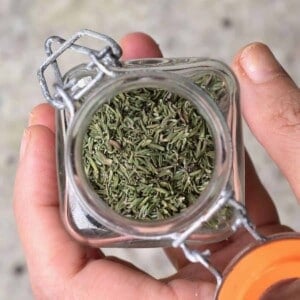 A hand holding a little jar with homemade dried thyme