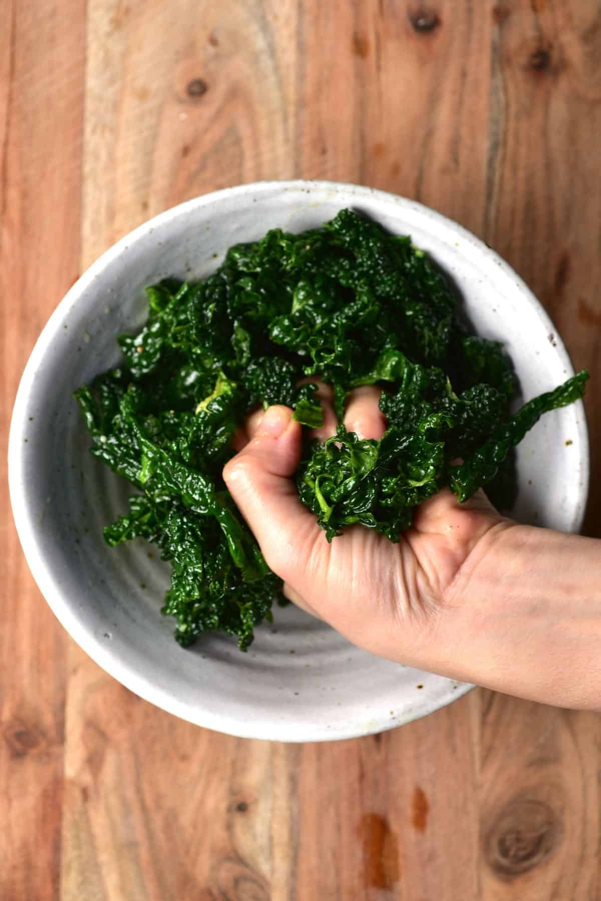 Massaging kale leaves in a bowl