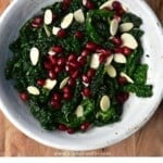 Kale salad with pomegranate seeds and flaked almonds in a bowl