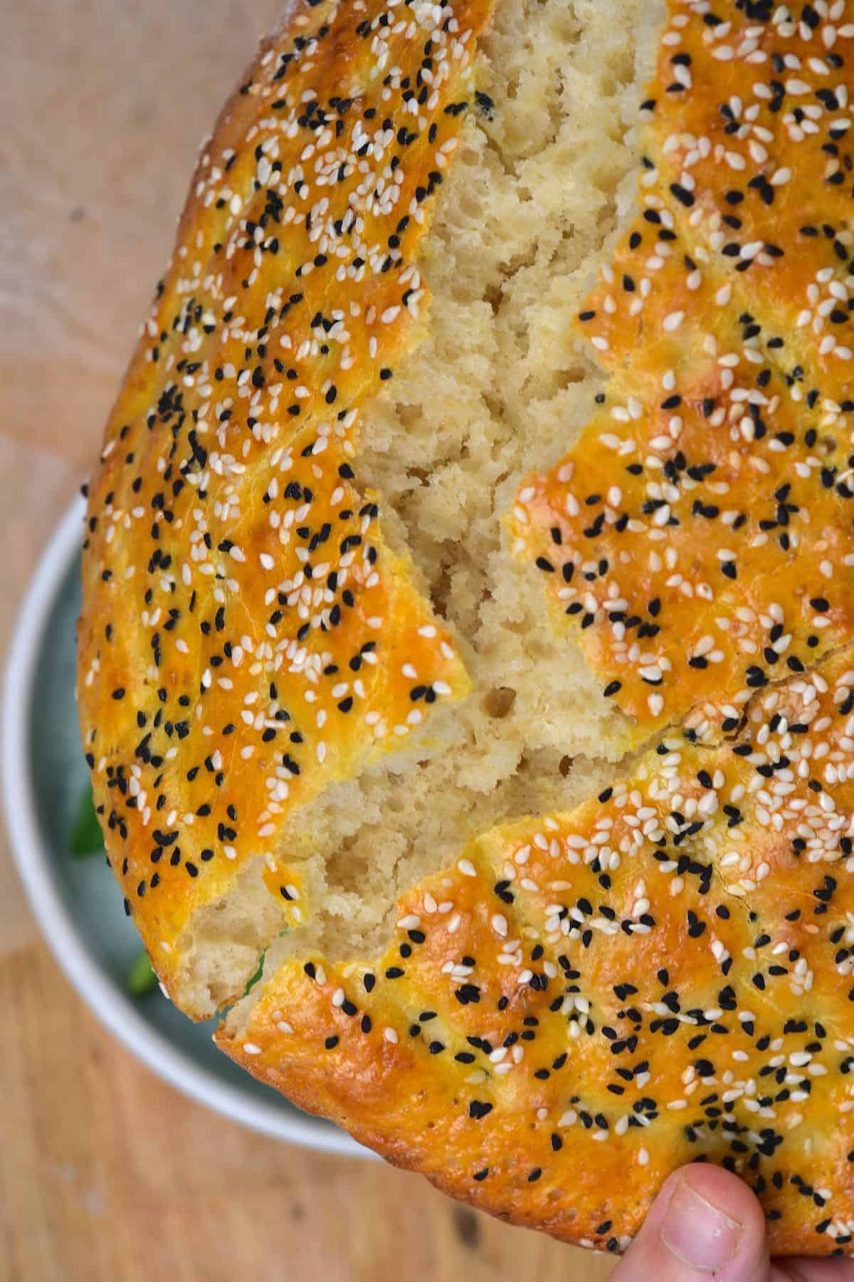 A close up of broken pide bread with nigella and white sesame seeds